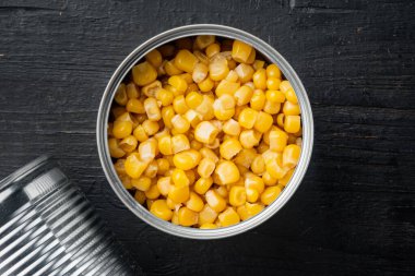 Konserve mısır konservesi, siyah ahşap masa arkaplanı, üst görünüm düz