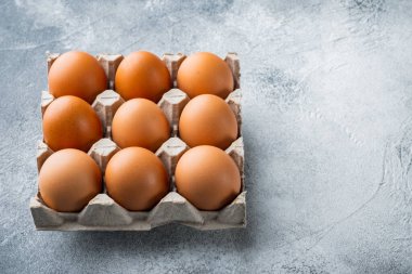 Gri arkaplandaki kutu tepsisinde kahverengi yumurtalar, metin kopyalama alanı için boşluk