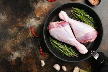 Çiğ hindi eti seti, dökme demir tavada, eski koyu kırsal masa zemininde, üst görünüm düz, metin alanı için fotokopi alanı