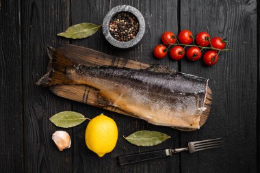 Tütsülenmiş alabalık seti, siyah ahşap masa arkaplanı, üst manzara düz.