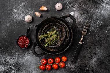 Siyah ahşap masa zemininde otlarla bezenmiş bofa balığı, düz bir manzarası var.