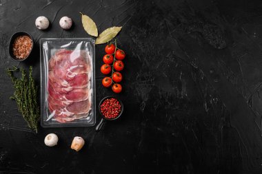 Prosciutto ham dilimler paketi seti, siyah taş masa arkaplanı üzerinde, üst görünüm düz, metin alanı için kopyalama alanı ile