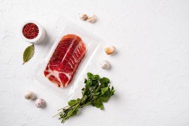 Dilimlenmiş Ham Salam Coppa plastik paket seti, beyaz taş masa arkaplanı üzerinde, üst görünüm düz, metin için metin alanı ile birlikte
