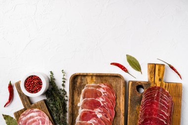 Prosciutto, salam, pastırma soslu soğuk tütsülenmiş et tabağı, beyaz taş masa zemininde, üst görünümü düz, metin alanı için fotokopi alanı