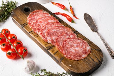 İnce dilimlenmiş Milano salamı seti, beyaz taş masa arkasında.
