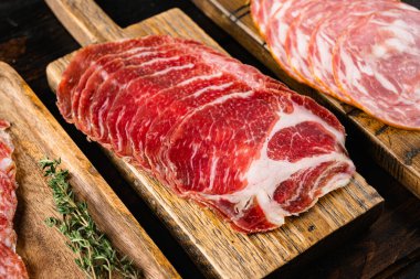 Dilimlenmiş sosisler, eski, siyah ahşap masa arkasında.