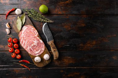 Tütsülenmiş sosis dilimleri, ince dilimlenmiş set, eski koyu ahşap masa arkaplanı, üst görünüm düz, metin alanı için fotokopi alanı