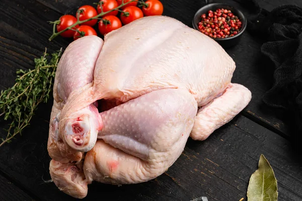 Çiğ tavuk seti, siyah ahşap masa arkasında.