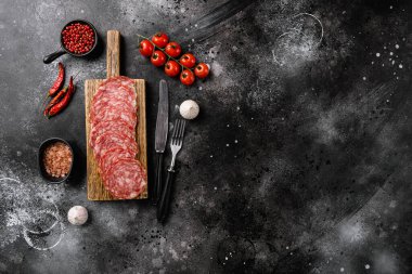 Salami Milano dilimlenmiş sosis seti, siyah taş masa arkaplanı, üst görünüm düz, metin alanı için kopyalama alanı ile