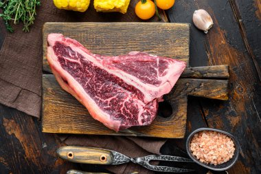 Kuru çiğ çiğ et ya da biftek mermer et. Bitki ve baharatlarla hazırlanmış biftek. Eski, siyah ahşap masa arka planında.