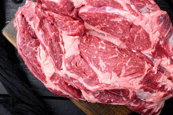 Бифштекс из ребрышек свежий сырой говядины мраморное мясо набор рибай, на черном фоне деревянный стол, вид сверху квартира