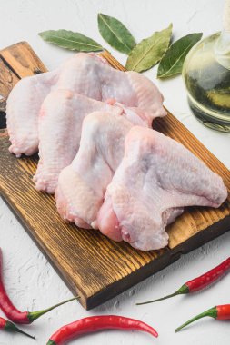 Fresh raw chicken wings with spices and herbs set, on wooden cutting board, on white background