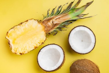 Exotic fresh fruits, pineapple and Coconut set, on yellow textured summer background, top view flat lay