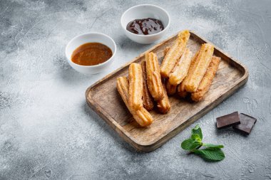 Churros with sugar, and chocolate sauce, on gray background with space for text, copyspace