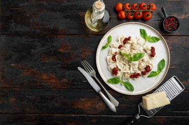Ravioli pasta with mushroom cream sauce and cheese - Italian food style set with basil parmesan and tomatoe  on white plate  on old dark  wooden table background, top view flat lay , with copyspace  and space for text