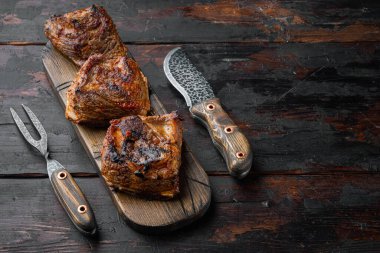 Tender cooked ribs in a delicious, rich sauce set, on old dark  wooden table background, with copy space for text