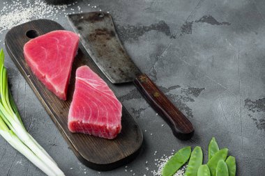 Raw tuna fillet. Seafood with sugar green pea, sesame and ingredients set, on wooden cutting board, and old butcher cleaver knife, on gray stone background , with copyspace  and space for text