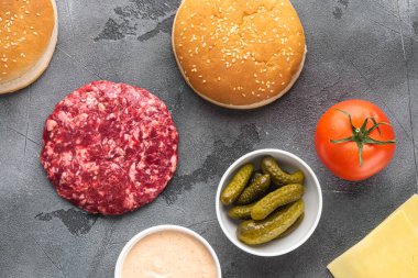 Sığır burger malzemeleri seti, gri taş zemin üzerinde, üst görünüm düz yatıyordu