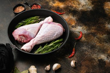 Turkey drumstick fresh meat set, on frying cast iron pan, on old dark rustic table background, with copy space for text