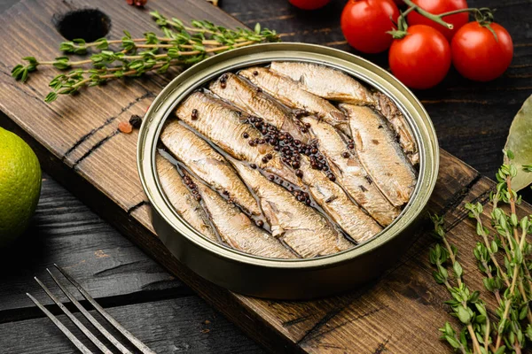 Canned fish in tin can with sardine set, on black wooden table background