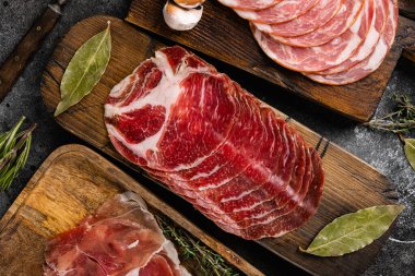 Italian sliced cured sausage set, on black dark stone table background, top view flat lay