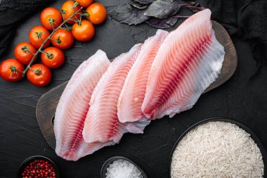 Beyaz balık filetosu, basmati pilavı ve kiraz domatesli, siyah arka planda, üst tarafta.