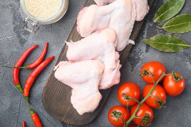 Raw meat. Chicken wings with vegetables and spices set, and sesame, on wooden cutting board, on gray background, top view flat lay