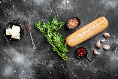 Ingredients for Garlic and gerbs bread Baguette set, on black dark stone table background, top view flat lay, with copy space for text
