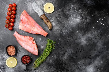 Whole raw red snapper fish set, on black dark stone table background, top view flat lay, with copy space for text