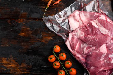 Piece of raw lamb meat set, with ingredients and herbs, on old dark  wooden table background, top view flat lay, with copy space for text