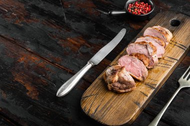 Izgara ördek göğsü seti, ahşap servis tahtasının üzerinde, eski koyu ahşap masa zemininde, kopyalanacak yeri ve metin için yeri var.