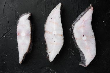 Donmuş beyaz balık filetoları, pollock seti, siyah taş masa arkaplanı, üst görünüm düz