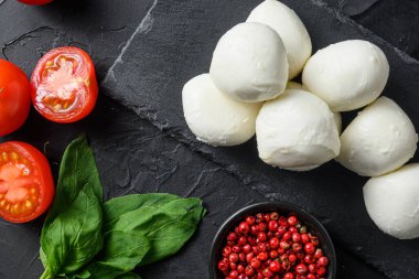 Taze kiraz domatesleri, fesleğen yaprağı, siyah tahta üzerinde mozzarella peyniri sağlıklı İtalyan geleneksel Caprese salatası malzemeleri. Organik Akdeniz gıda konsepti, düz konum yakın yatış.