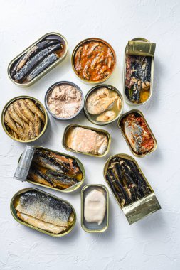 Saury, uskumru, ispinoz, sardalya, sardalya, kalamar, mürekkep balığı, beyaz desenli taş sehpanın üzerine konserve konserve kutuları dikey olarak yatıyordu..