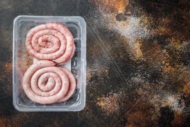 Çiğ spiral sosis seti, eski koyu kırsal arka planda, plastik pakette, üst görünüm düz yerde, metin kopyalama alanı için yer var