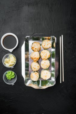 Sushi, siyah taş arka planda, metin için metin alanı ve boşluğu olan, üst görünüm düz yatağında, paket kutusu setinde yuvarlanır.