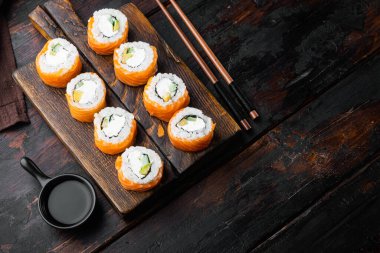 Geleneksel taze Japon suşi ruloları seti, eski siyah ahşap masa arka planında, metin için metin alanı ve boşluğu ile