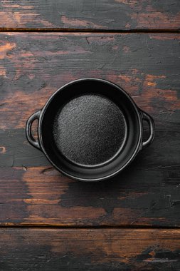 Metin veya yemek için kopyalama alanı olan siyah pişirme tenceresi seti, üst görünüm düz, eski koyu ahşap masa arkaplanı üzerinde