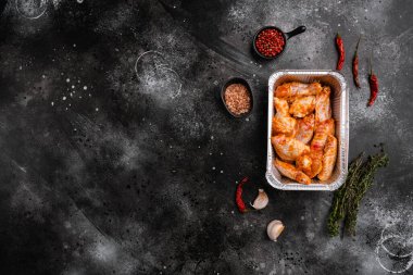 Baharatlı çiğ tavuk kanatları, siyah taştan masa arkaplanı, üst görünüm düz, metin alanı için kopyalama alanı