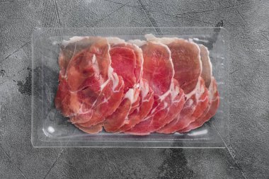 Dilimlenmiş prosciutto seti, gri taş masa arkaplanı, üst görünüm düz yatıyordu
