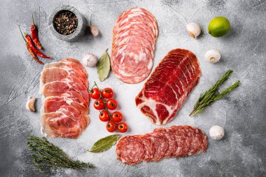 İyileştirilmiş İtalyan eti jambonu, jambon, pancetta seti, gri taş masa zemininde, üst manzara düz.