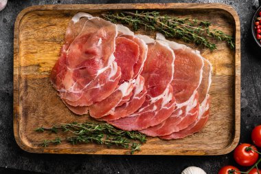 Prosciutto geleneksel İspanyol dilimleri, siyah taş masa arkasında, üst görünüm düz yatıyordu