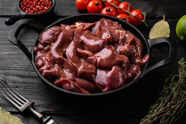 Taze ördek ciğeri sakatatı seti, siyah ahşap masa arkasında.