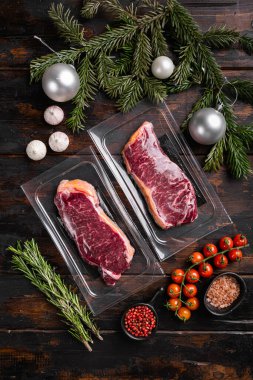 Yeni yıl seti için New York biftek paketi, eski koyu ahşap masa arkaplanı, üst görünüm düz yatıyordu