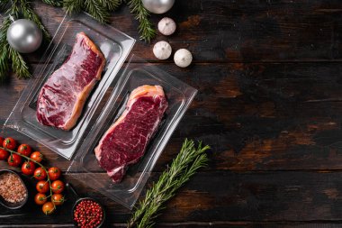 Çiğ mermer biftek vakumlama seti, eski koyu ahşap masa arkaplanı üzerinde, üst görünümü düz, metin alanı için kopyalama alanı ile