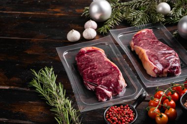 Vakum paketleme seti içindeki et, eski koyu ahşap masa arkaplanı üzerinde, metin için kopyalama alanı ile