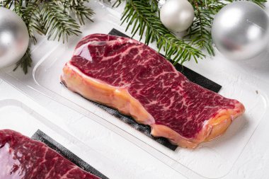 Noel ve Yeni Yıl seti için, beyaz taştan masa arkaplanına sığır eti konmuş biftek paketi