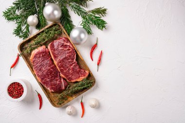 Yeni yıl için çiğ Striploin mermer biftek seti, beyaz taş masa arkaplanı, üst görünüm düz, metin alanı için fotokopi alanı