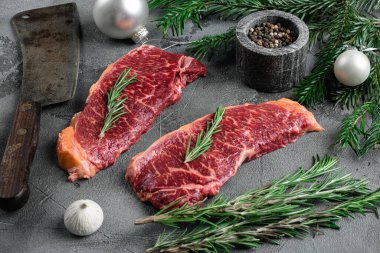 Gri taştan masa arkasında çiğ biftekler.