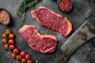 Çiğ çizgili biftek seti, siyah taştan masa arkaplanı, üst manzara düz.